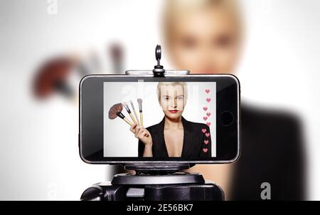 Frau Schönheit Vlogger. Videoclip von Smartphone Sharing auf Social Media. Mode Blogger Make-up Artist Live Kosmetik Make-up Tutorial. Mädchen mit Visage Stockfoto