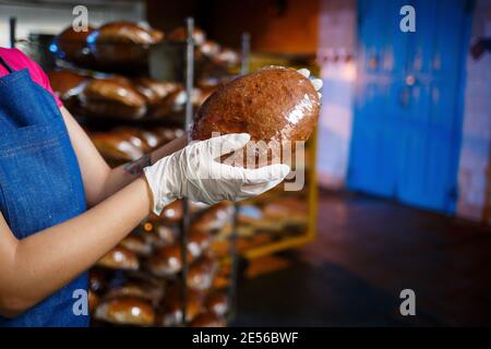 Mädchen Bäcker arbeitet in einer Bäckerei. Frisches knuspriges Brot aus nächster Nähe Stockfoto