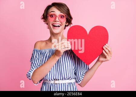 Foto Porträt der aufgeregt Frau mit großen roten Herz-Karte Mit zwei Händen tragen rosa getönte Gläser isoliert auf pastellrosa Farbiger Hintergrund Stockfoto