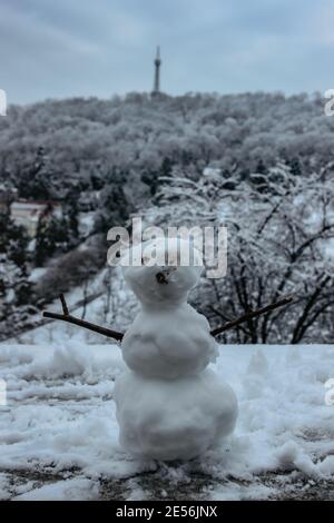 Frostiger Schneemann und Petrin Hügel mit Aussichtsturm im Hintergrund selektive Fokus.Prag Winterpanorama, Tschechische Republik. Schneereichen Wintertag in der Stadt.Winter Stockfoto