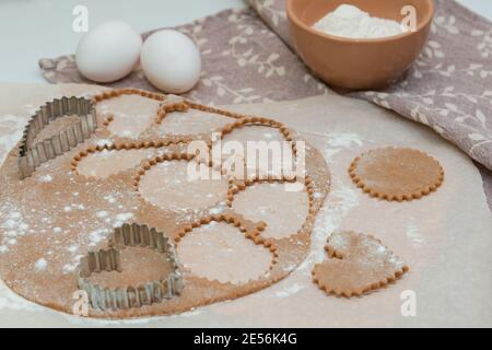 Ausschneiden von herzförmigen Plätzchen aus rohem Teig mit Ausstechformen. Stockfoto