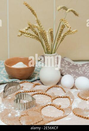 Ausschneiden von herzförmigen Plätzchen aus rohem Teig mit Ausstechformen. Stockfoto