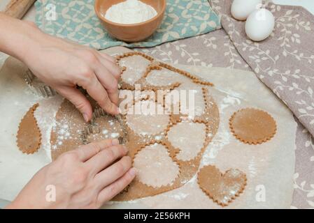 Verfahren des Schneidens von Cookies durch Ausstechformen. Frau, die mit den Händen macht, bildet Kekse aus rohem Teig Stockfoto