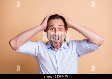Portrait von schönen glücklich fröhlich Mann mittleren Alters große Nachrichten Reaktion isoliert über beige Pastellfarbe Hintergrund. Stockfoto