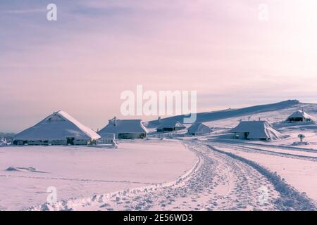 Winterlandschaft mit schneebedeckten Hirtenhütten in Bergen. Velika planina in Slowenien. Stockfoto