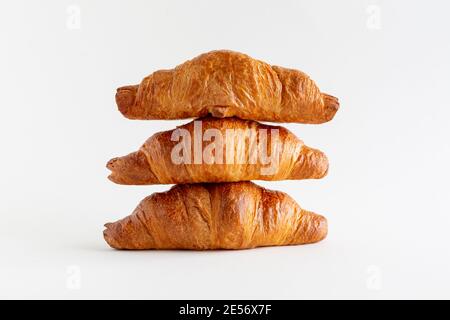 Drei frisch gebackene Croissants übereinander gestapelt auf weißem Hintergrund, horizontal, Nahaufnahme Stockfoto