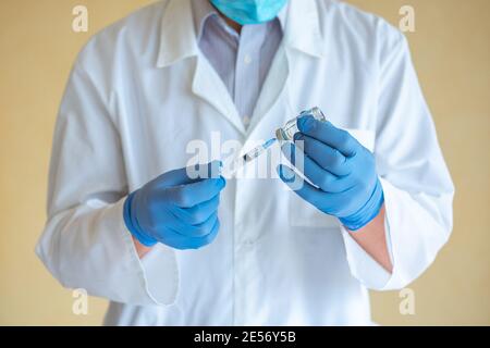 Arzt Mann in blauen Latexhandschuhen wählt einen Impfstoff in Eine Nahaufnahme der Spritze Stockfoto