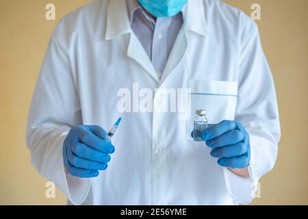 Arzt Mann in blauen Latexhandschuhen hält Spritze und Ampulle Mit Nahaufnahme des Impfstoffes Stockfoto
