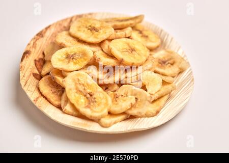 Dehydrierte Banane in Holzplatte isoliert auf weißem Hintergrund. Stockfoto