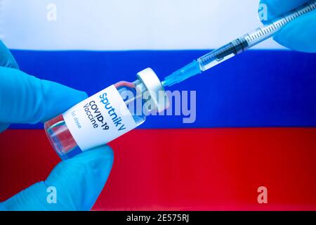Calgary, Alberta. Kanada. Januar 20 2021. Ein Gesundheitshelfer mit Spitnik V-Impfstoff und einer Spritze mit russischer Flagge im Hintergrund Stockfoto