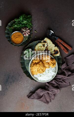 Indisches Butter-Huhn mit Basmati-Reis, Gewürze, Naan-Brot. Zwiebelsalat, Brauner Hintergrund. Leerzeichen für Text Stockfoto