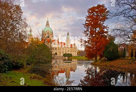 Die leuchtend roten und gelben Herbstbäume im Maschpark mit Blick auf den Maschteich-See und das Neue Rathaus, Hannover, Deutschland Stockfoto