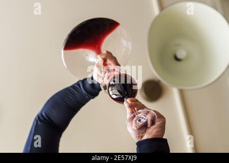 Nahaufnahme der Hände eines unbekannten kaukasischen Mannes, der rot goss Wein aus der Flasche im Dekanter zu Hause am Tag - niedriger Winkel Ansicht Kopieplatz Stockfoto