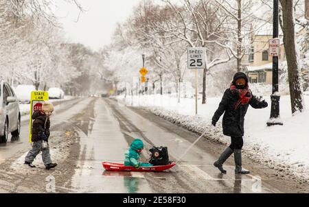 Chicago, USA. Januar 2021. Eine Frau und ihre Kinder überqueren am 26. Januar 2021 eine Straße in Evanston, nördlich von Chicago, Illinois, USA. Ab Montagabend kam es in Chicago zu einem Wintersturm. Bis 9 Uhr Ortszeit Dienstag, waren die Schneesummen in einigen Teilen der Chicago-Gegend nahe an 8 Zoll gekommen. Quelle: Joel Lerner/Xinhua/Alamy Live News Stockfoto