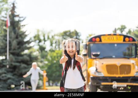 Kids Student läuft in die Hände der Mutter, um sie nach zu umarmen Zurück zur Schule in der Nähe des Schulbusses Stockfoto
