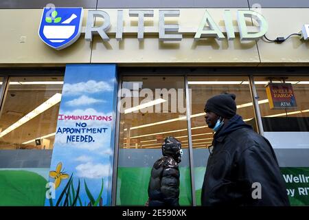 New York, USA. Januar 2021. Zwei Menschen passieren einander, während sie entlang der 125th Street in der Harlem Nachbarschaft von Manhattan, New York, NY, 26. Januar 2021 gehen. Afroamerikanische Gemeinschaften sind überproportional von COVID-19-Infektionen betroffen, die dreimal so hoch sind wie weiße Gemeinschaften und sich stark auf ihr Geschäft und ihre Gemeinden auswirken. (Foto von Anthony Behar/Sipa USA) Quelle: SIPA USA/Alamy Live News Stockfoto