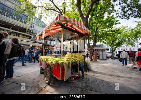 Istanbul / Türkei - Mai 02 2019 : Autostand mit gekochtem Mais der Kaufmann ist ein junger Mann unter einem großen Baum vor dem Großen Basar Markt in Th Stockfoto