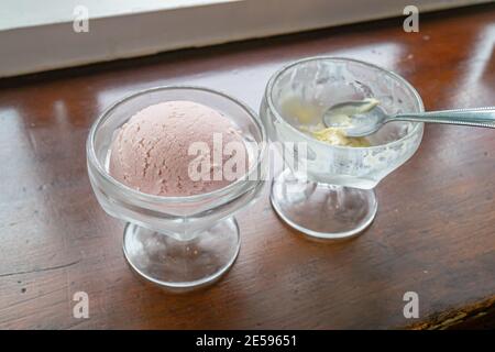 Die Nahaufnahme von leckeren hausgemachten kühlen Erdbeer Eis Schaufel in Glas Tasse auf Vintage Holz Tisch Hintergrund. Stockfoto