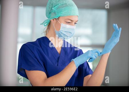 Krankenschwester mit einer Maske, die Handschuhe aufsetzt Stockfoto