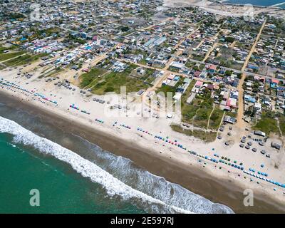 Luftdrohnenansicht des Strandes, der Touristen, des Meeres und der Wellen, die in der Küste der Stadt Playas General Villamil, Ecuador planschen. Sonniger Tag. Stockfoto