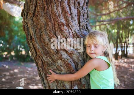 Mädchen umarmt Baum im Park. Stockfoto