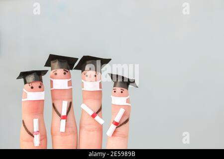 Finger Kunst von Studenten in medizinische Maske aus COVID-2019. Absolventen, die ihr Diplom nach dem Abschluss halten. Stockfoto