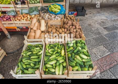 Zucchini, Kartoffeln, Zwiebeln, Knoblauch und andere verschiedene Lebensmittel auf dem Display neben dem Kai und Kotor Bay. Stockfoto