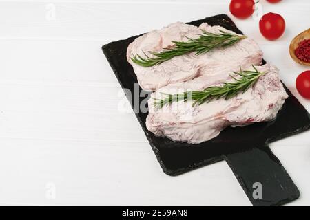 Zwei marinierte Roh-Rindersteaks auf schwarzem Steinbrett Stockfoto