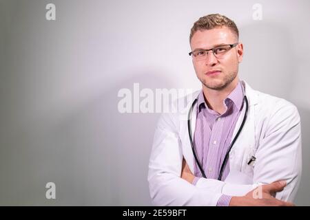 Ernst attraktiven jungen männlichen Arzt trägt weißen Laborkittel suchen Bei der Kamera Stockfoto