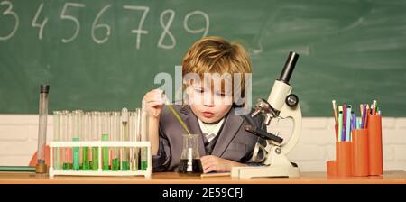 Schulbildung. Untersuchen Sie biologische Moleküle. Baby mit einem kleinen Genie. Technologie- und Wissenschaftskonzept. Junge in der Nähe von Mikroskop und Reagenzgläsern im Schulunterricht. Kid studiert Biologie und Chemie in der Schule. Stockfoto