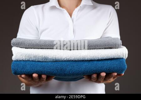 Eine Frau hält einen Stapel von sauberen, gerollten Handtüchern. Stockfoto