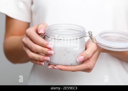 Ein junges Mädchen hält ein offenes Glas kosmetischer Creme in den Händen. Hautpflegekonzept, Jugendlichkeit und Elastizität der Haut. Stockfoto