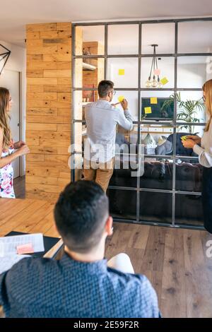 Geschäftsleute in einem Arbeitsmeeting, auf dem Haftnotizen platziert werden Die Wand Stockfoto