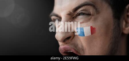 Ein schreiender Mann mit dem Image des französischen Nationales Flagge auf seinem Gesicht Stockfoto