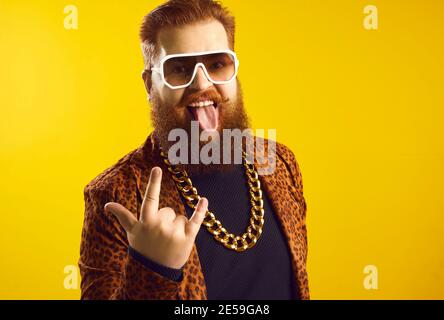 Lustige exzentrische bärtige Mann in extravaganten Outfit tun Horn Zeichen Und die Zunge herausstreckt Stockfoto