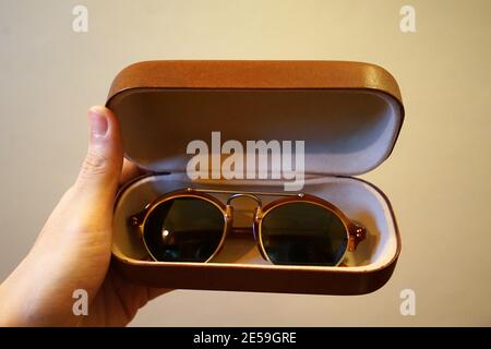 Nahaufnahme Hand mit geöffneter Lederbox mit Sonnenbrille Stockfoto