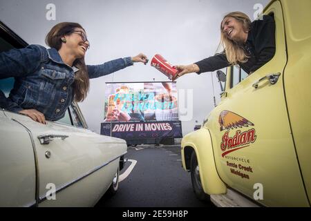 Datei Foto vom 27/08/2020 der Filmbesucher Ruth Wyatt (links) und Loraine Preston teilen Süßigkeiten, bevor sie sich den Film Sunshine on Leith in ihren Oldtimern in der sozial distanzierten Drive-in Movie Arena ansehen, die im Rahmen des Edinburgh International Film Festival am Flughafen Edinburgh eingerichtet wurde. Am Samstag, den 30. Januar, jährt sich der früheste bekannte Tod des Coronavirus in Großbritannien zum ersten Mal. Ausgabedatum: Mittwoch, 27. Januar 2021. Stockfoto