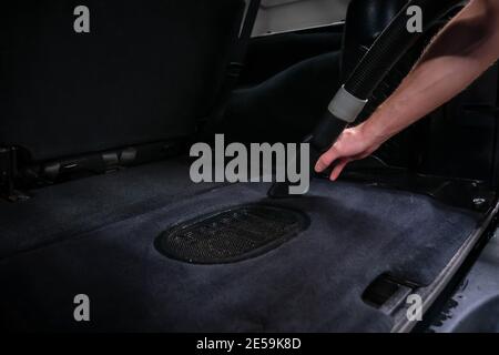 Nahaufnahme der Autowaschanlage Arbeiter saugen Kofferraum. Reinigung der Autowäsche. Stockfoto