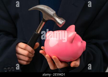 Nahaufnahme des jungen Unternehmers Schlagen Sparschwein mit einem Hammer. Stockfoto
