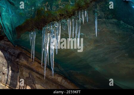 Scharfe Eiszapfen hängen am Rand des Balkons. Schmelzender Schnee bildet Eiszapfen. Stockfoto