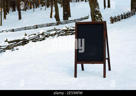 Nahaufnahme des Kreidetafelmenüs draußen auf dem Schnee. Winter-Menü-Anzeige in den Bergen. Stockfoto