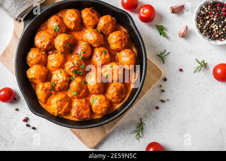 Hausgemachte Fleischbällchen in Tomatensauce aus nächster Nähe. Fleischbällchen aus Gusseisen auf weißem Hintergrund. Stockfoto
