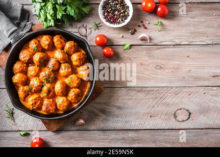 Hausgemachte Fleischbällchen in Tomatensauce, Draufsicht, Kopierraum. Fleischbällchen aus Gusseisen auf Holzboden. Stockfoto