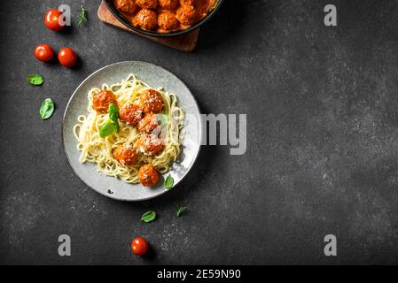Spaghetti Pasta mit Fleischbällchen, Tomatensauce, geriebenem Käse und frischem Basilikum - gesunde hausgemachte italienische Pasta auf schwarzem Hintergrund, Draufsicht, Kopierraum Stockfoto