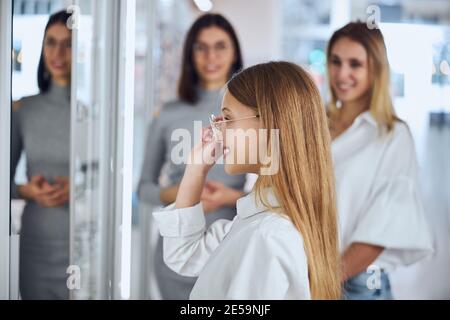 Glücklich lächelnd Teenager-Mädchen in weißem Hemd Blick auf die Spiegel im Zimmer drinnen Stockfoto