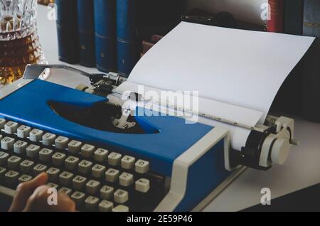 Vintage-Foto von alten Büchern. Die Hand des Schriftstellers ist auf der Schreibmaschine .Writer Schreiben eines Liebesromans. Romancier schreibt Roman auf einer Schreibmaschine Stockfoto