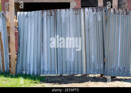 Ein alter klappriger Zaun aus Aluminium und Holz. Eiserner Ringzaun. Stockfoto