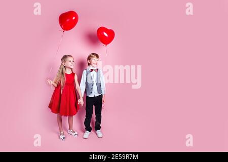 Valentinstag. Zwei glückliche Kinder mit herzförmigen Luftballons auf rosa Studio Hintergrund Stockfoto