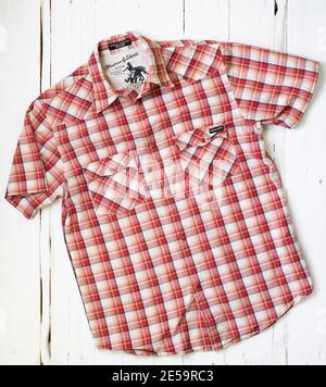 Ein rot kariertes Volcom Shirt auf weißem Holzhintergrund Stockfoto