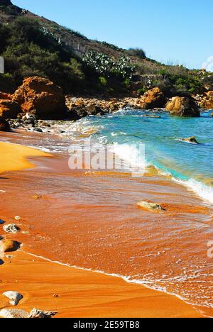 Felsige Küste und roter Sand San Blas Beach in Nadur Gozo Stockfoto